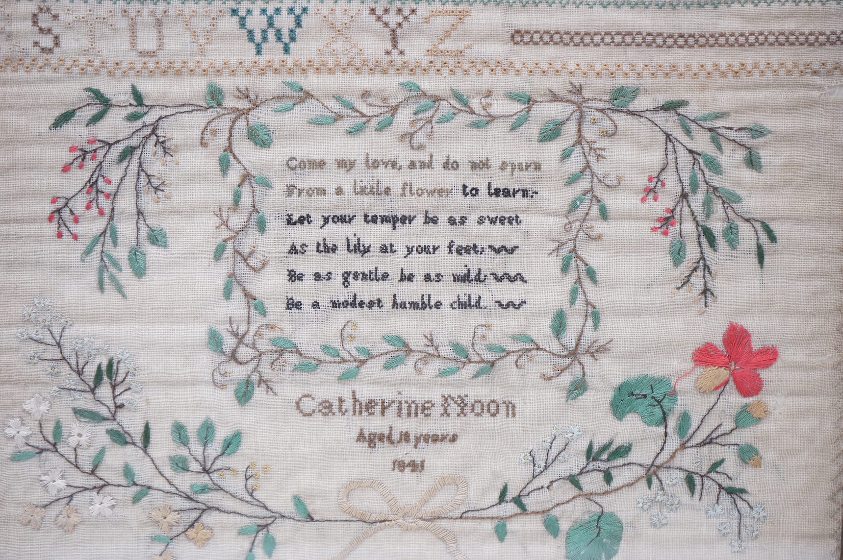 A framed 19th century alphabet sampler by Catherine Noon, dated 1841. Embroidered at the top with a harp and two birds and rows of alphabet and numbers, a central cartouche of verse below and her name and date above a fl
